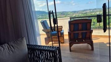 A room with a large window, a sofa, and a wooden chair.