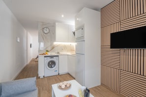 Una cocina moderna con lavadora integrada, microondas y televisor de pantalla plana montado en la pared.
