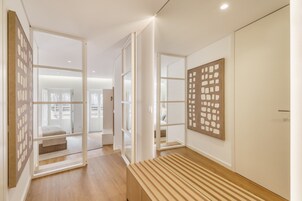 Un interior moderno con un banco de madera, puertas de cristal y una obra de arte colgada en la pared.