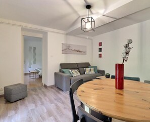 Ein modernes Wohnzimmer mit einem grauen Sofa, einem Holzesstisch und einer roten Vase mit Blumen.
