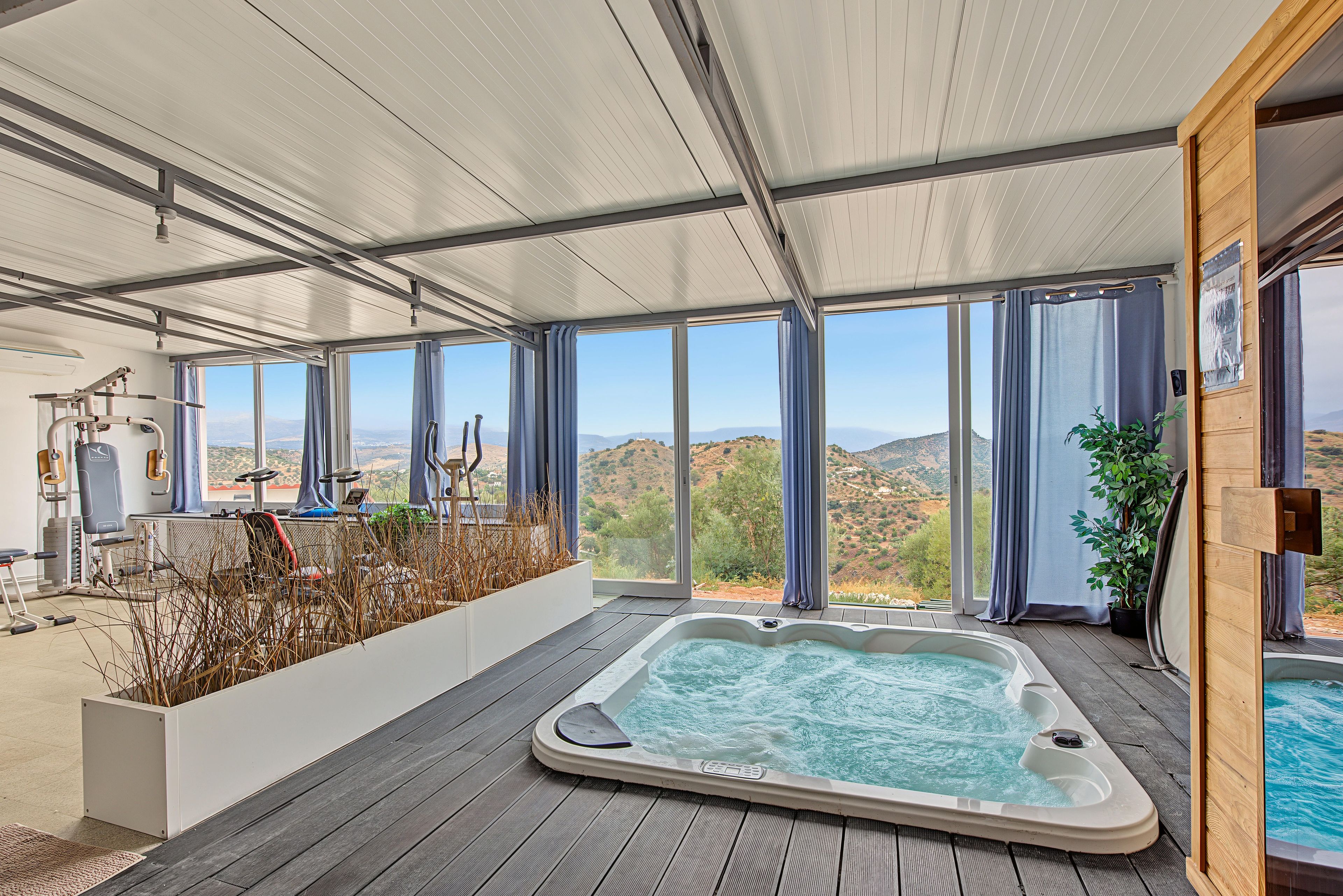 A spa area with a hot tub, exercise equipment, and a view of the landscape.