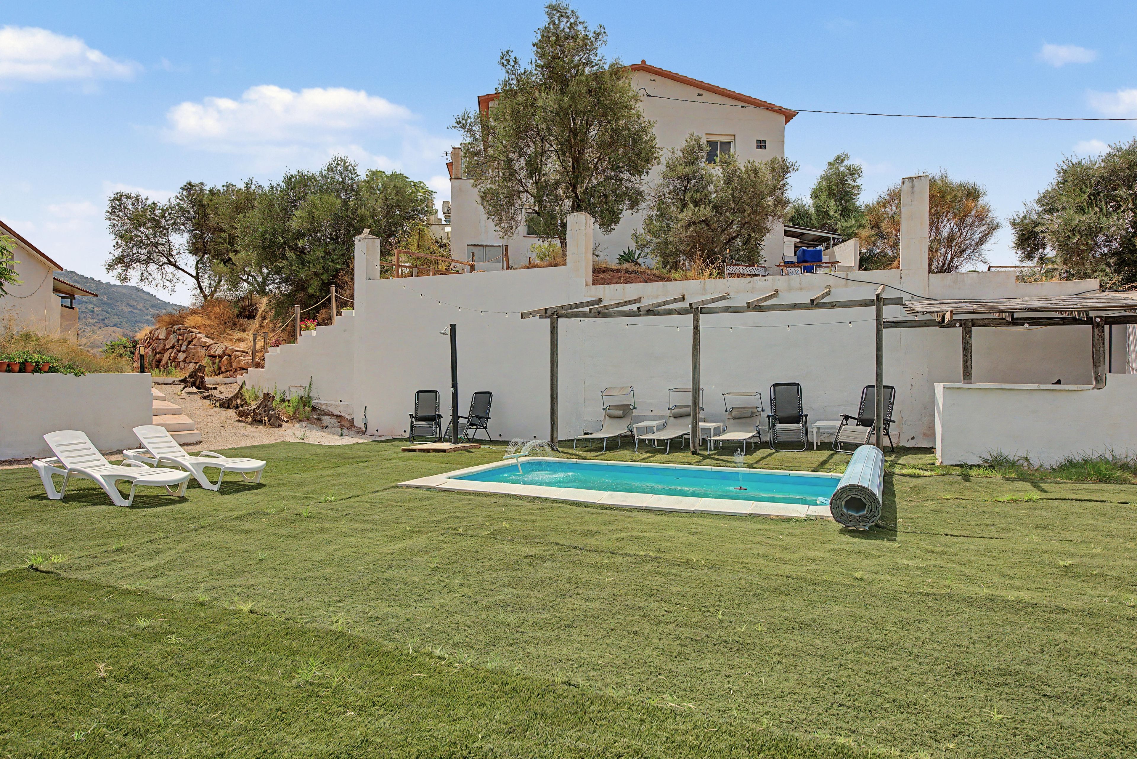 A backyard with a swimming pool, lounge chairs, and a pergola.