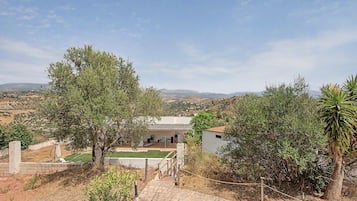 A residential property with a patio, a view of the countryside, and a solar panel roof.