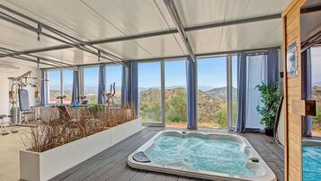Un área de spa con un jacuzzi, equipo de ejercicios y vistas al paisaje.