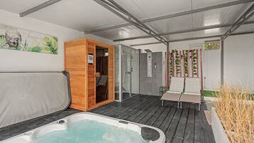 A spa area with a hot tub, wooden sauna, and a glass-enclosed shower.