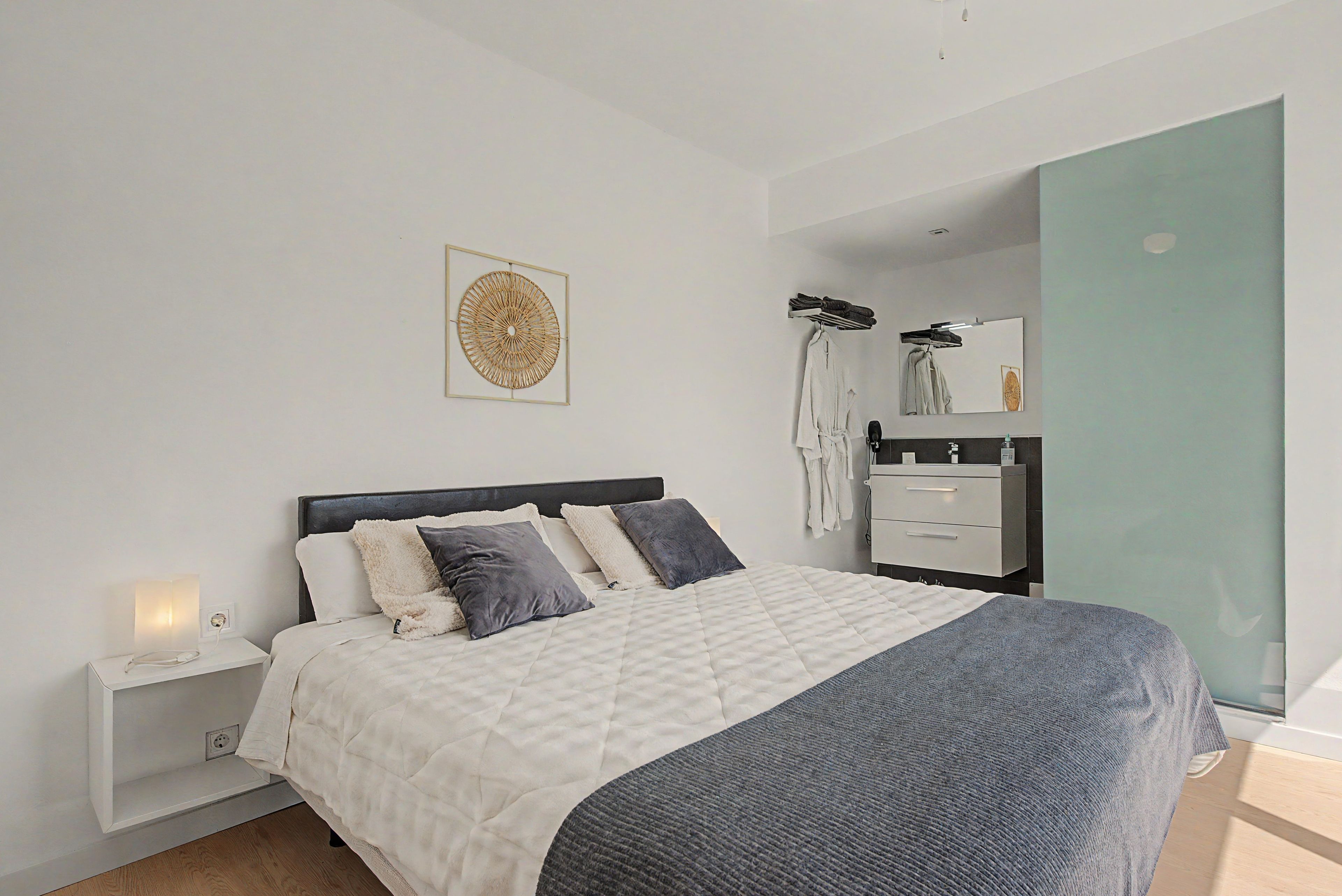 A modern bedroom with a bed, bedside table, and a wall-mounted artwork.