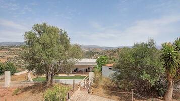 A residential property with a patio, a view of the countryside, and a solar panel roof.