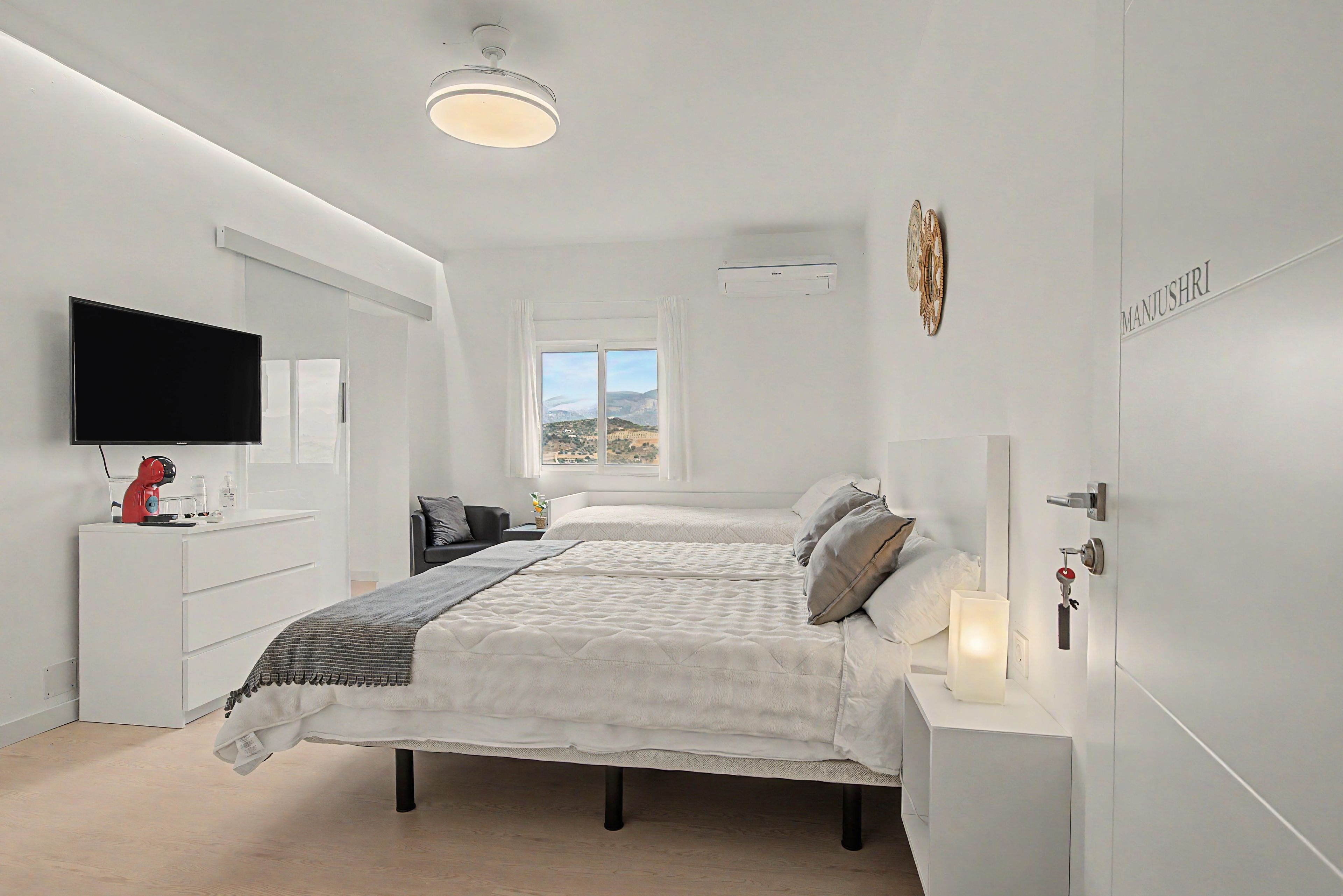 A modern bedroom with a bed, bedside table, and a TV on the wall.