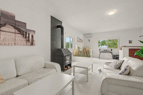 A modern living room with a fireplace, white furniture, and artwork on the walls.