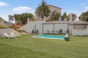 A backyard with a swimming pool, lounge chairs, and a pergola.