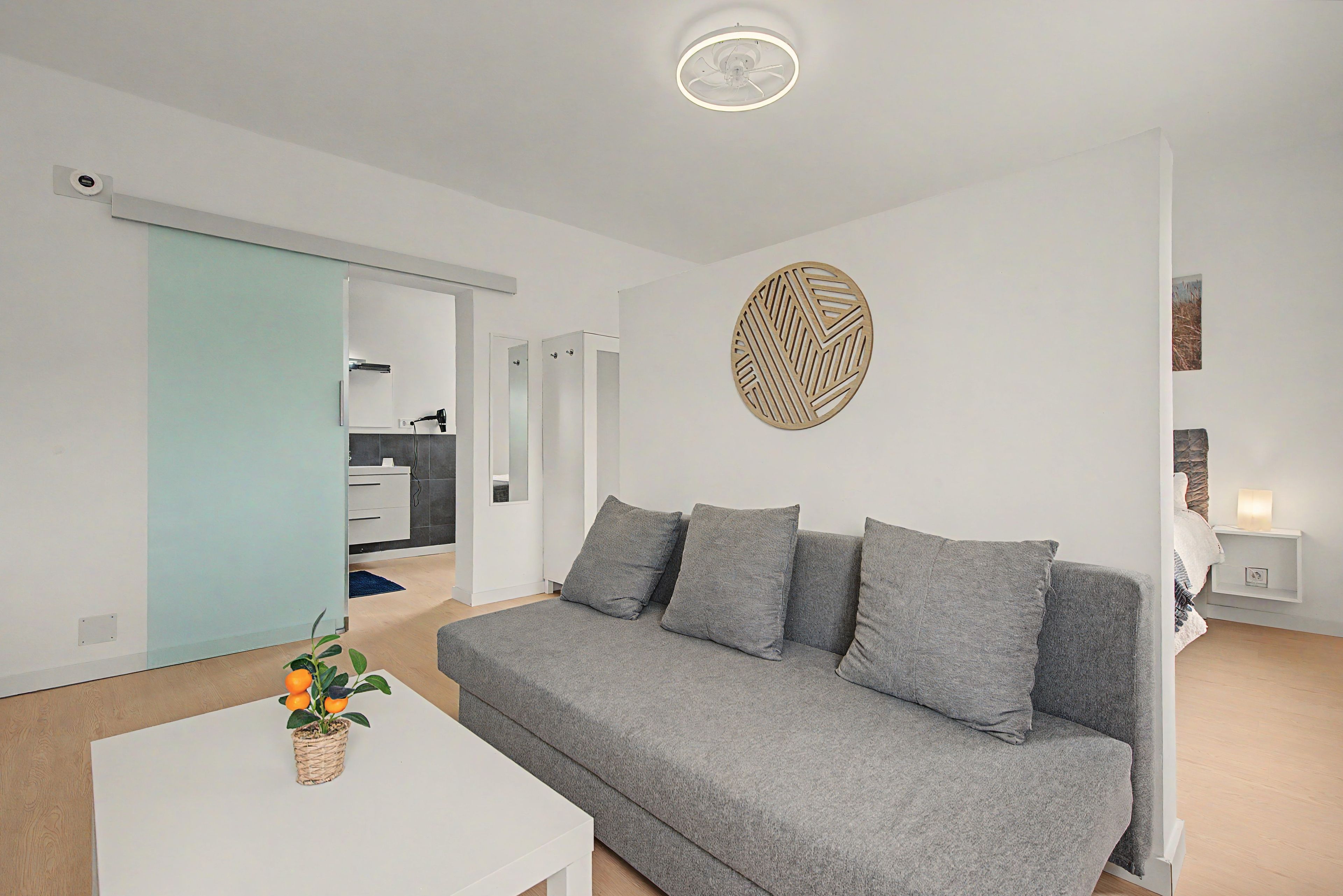 Una sala de estar moderna con un sofá gris, una mesa de centro blanca y un adorno de pared decorativo.