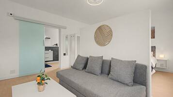 Una sala de estar moderna con un sofá gris, una mesa de centro blanca y un adorno de pared decorativo.