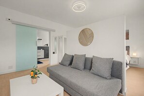 A modern living room with a grey sofa, a white coffee table, and a decorative wall piece. - Jingtu Wellness & Spa Vairochana (Romo Cuevas)