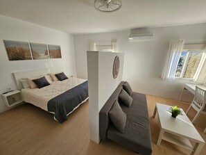 Een slaapkamer met een bed, een bank, een bureau en een raam met gordijnen.