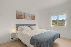 A bedroom with a bed, a nightstand, a window with a view, and wall art. - Jingtu Wellness & Spa Vairochana (Romo Cuevas)