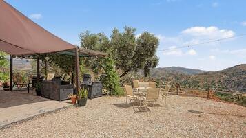 An outdoor seating area with tables and chairs, a pergola, and a view of the surrounding landscape.