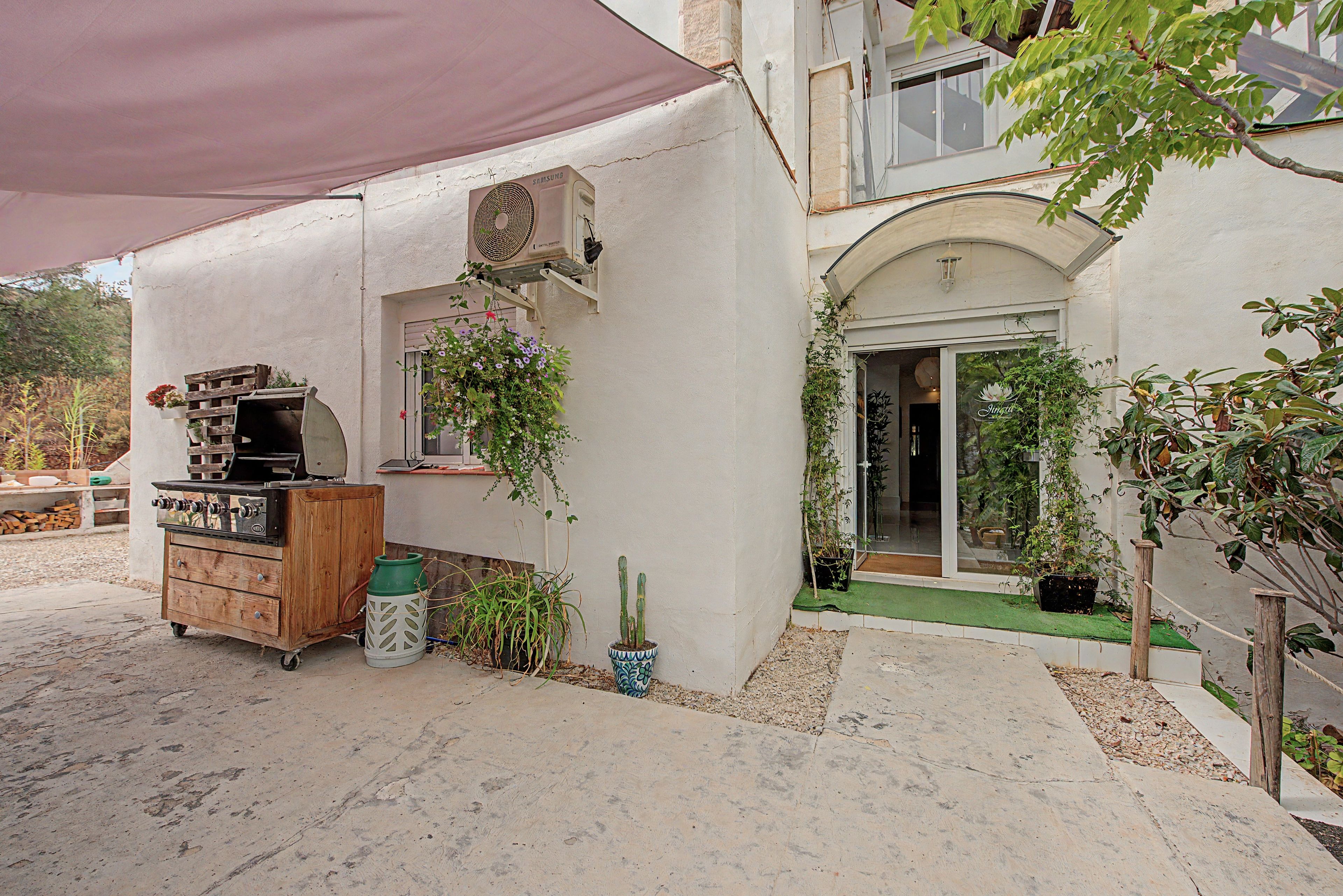 A patio area with a barbecue grill, a Samsung air conditioning unit, and various potted plants.