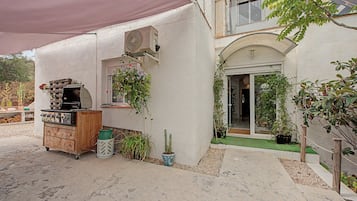 A patio area with a barbecue grill, a Samsung air conditioning unit, and various potted plants.