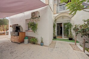 A patio area with a barbecue grill, a Samsung air conditioning unit, and various potted plants. - Jingtu Wellness & Spa Vairochana (Romo Cuevas)