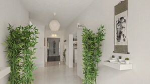 A hallway with a modern design, featuring a white floor, a hanging light fixture, and a wall-mounted shelf with small plants. - Jingtu Wellness & Spa Vairochana (Romo Cuevas)