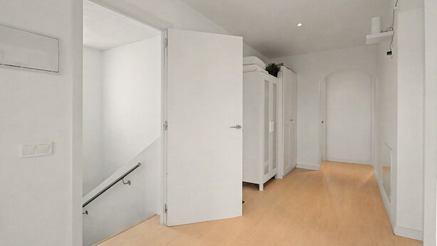 A hallway with white walls, wooden flooring, and a door leading to a room. - Jingtu Wellness & Spa Vairochana (Romo Cuevas)