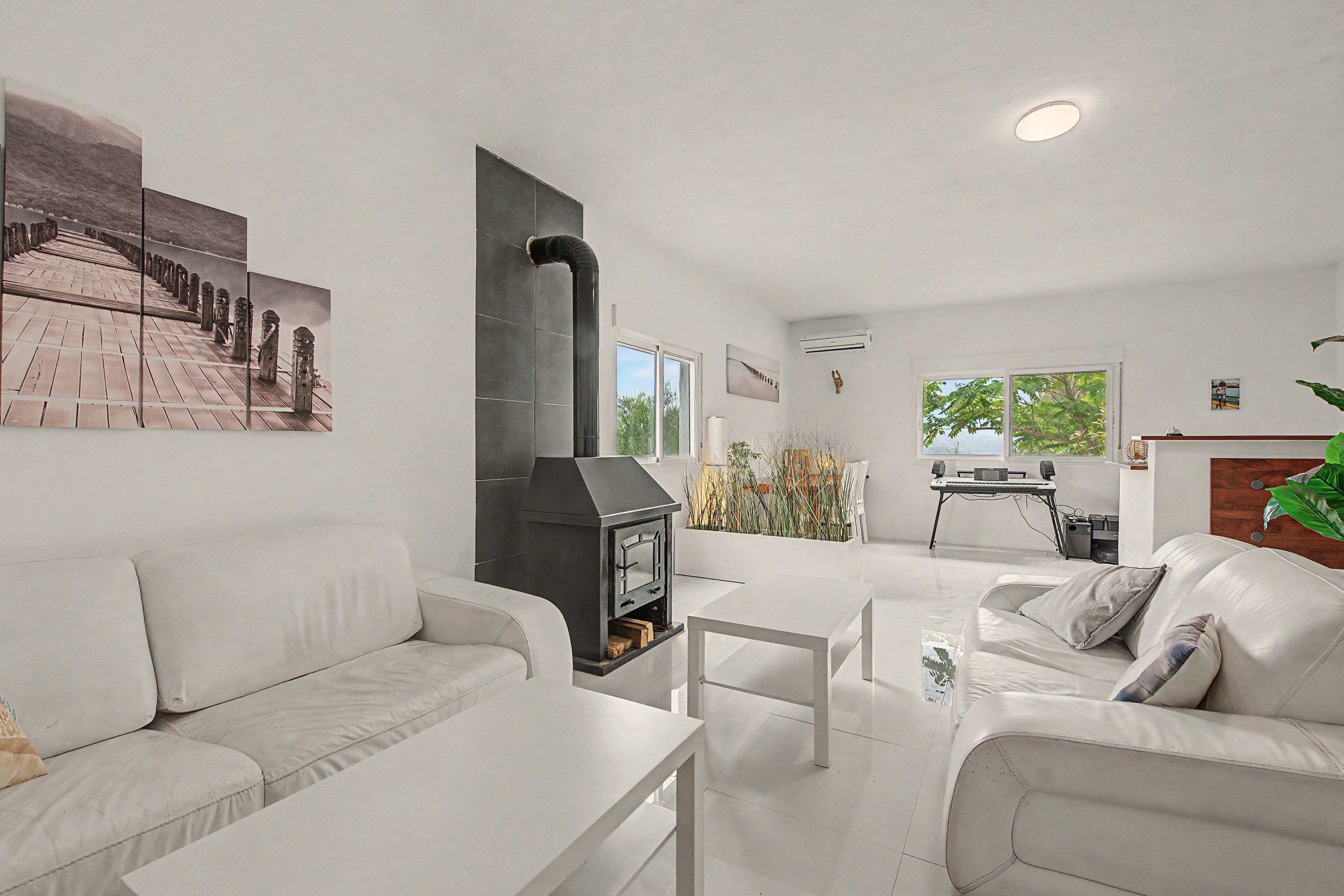 Una sala de estar moderna con chimenea, muebles blancos y obras de arte en las paredes.
