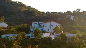 A multi-story building with a flat roof, surrounded by greenery and hills. - Jingtu Wellness & Spa Maitreya (Romo Cuevas)