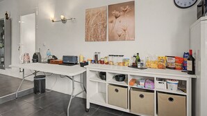 A kitchenette with a white countertop, a clock, and wall-mounted light fixtures. - Jingtu Wellness & Spa Maitreya (Romo Cuevas)
