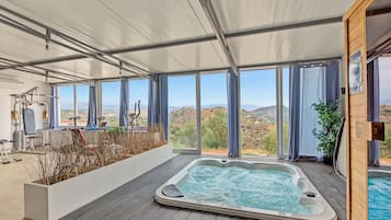 Een wellnessruimte met een bubbelbad, fitnessapparatuur en uitzicht op het landschap.