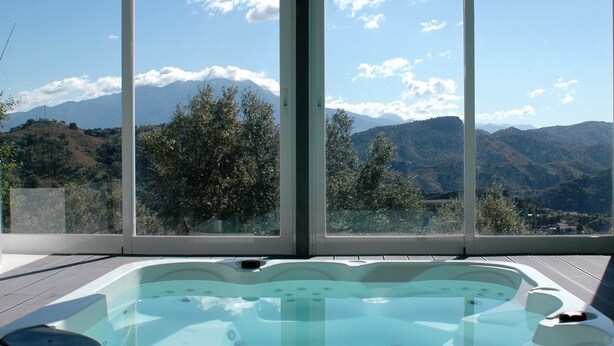 A hot tub with a mountain view through large windows. - Jingtu Wellness & Spa Maitreya (Romo Cuevas)