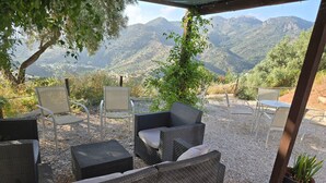 An outdoor seating area with wicker furniture, a pergola, and a view of mountains. - Jingtu Wellness & Spa Maitreya (Romo Cuevas)