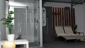 A modern bathroom with a glass shower enclosure, a wooden sauna, and a sun lounger. - Jingtu Wellness & Spa Maitreya (Romo Cuevas)