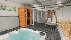A spa area with a hot tub, wooden sauna, and a glass-enclosed shower. - Jingtu Wellness & Spa Maitreya (Romo Cuevas)