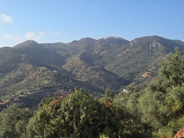 Un paisaje montañoso con un edificio pequeño en una colina.