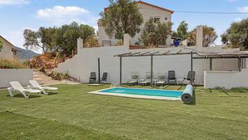 Ein Garten mit Swimmingpool, Liegestühlen und einer Pergola.