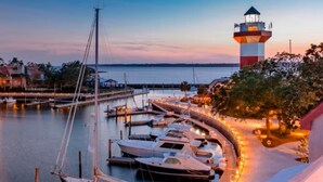 Ein Yachthafen mit vertäuten Booten, einem Leuchtturm und Blick auf das Wasser.