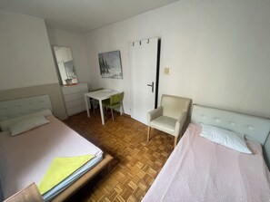 Een slaapkamer met twee bedden, een bureau, een stoel en een deur.