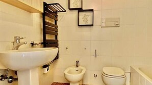 A bathroom with a sink, bidet, toilet, and a towel rack. - Hostdomus - Bay Apartment (Laigueglia)