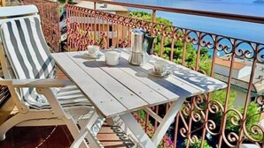 A balcony with a table, chairs, and a view of the sea and mountains. - Hostdomus - Bay Apartment (Laigueglia)