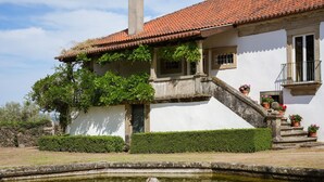 Un bâtiment dot é d’un toit en tuiles, d’un escalier en pierre et d’un petit jardin avec un bassin.