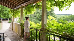 Un espace extérieur abrité, doté de colonnes en pierre et d’une terrasse en bois.