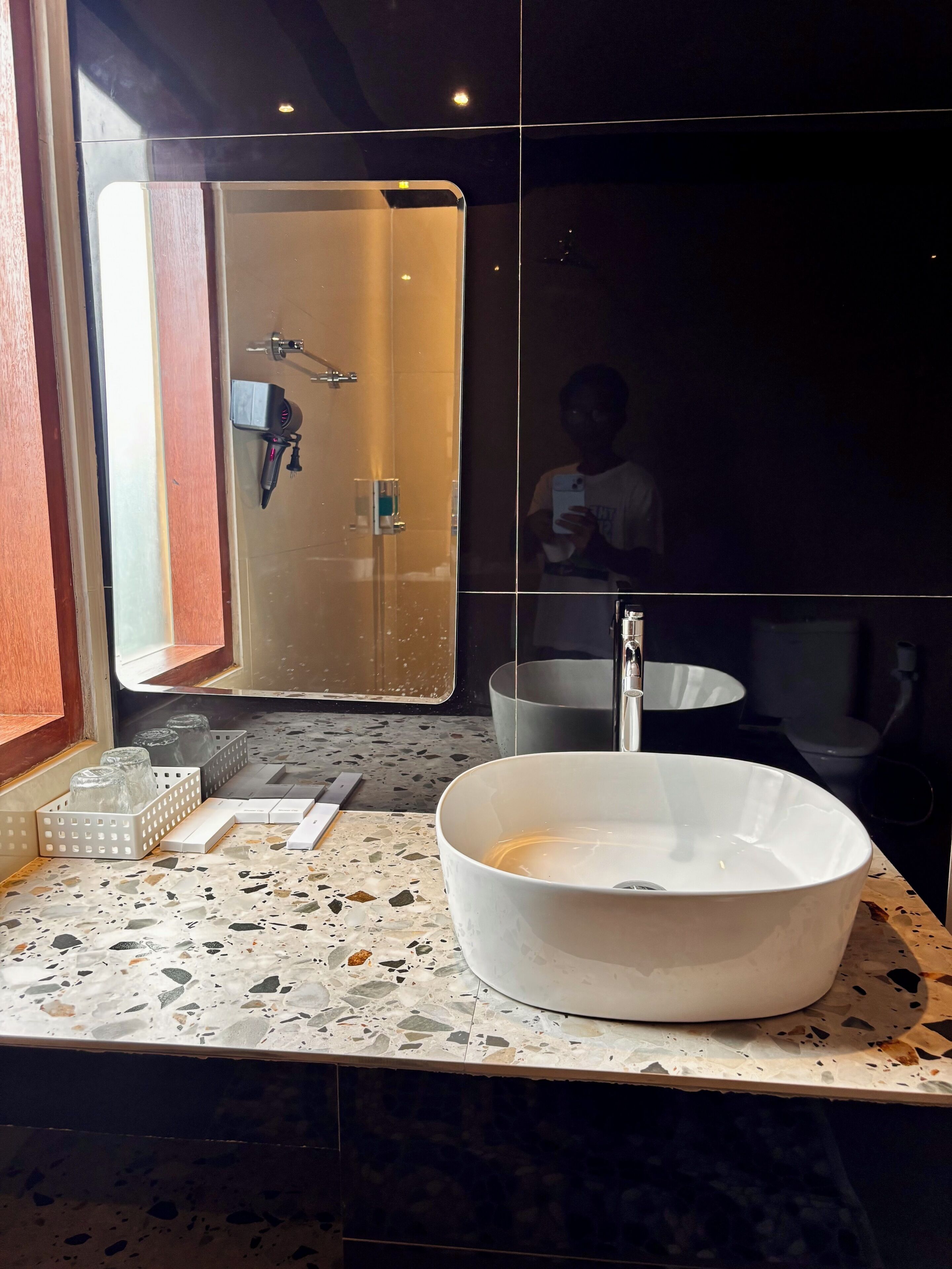 Une salle de bain avec un grand miroir, un lavabo rond et un espace douche.