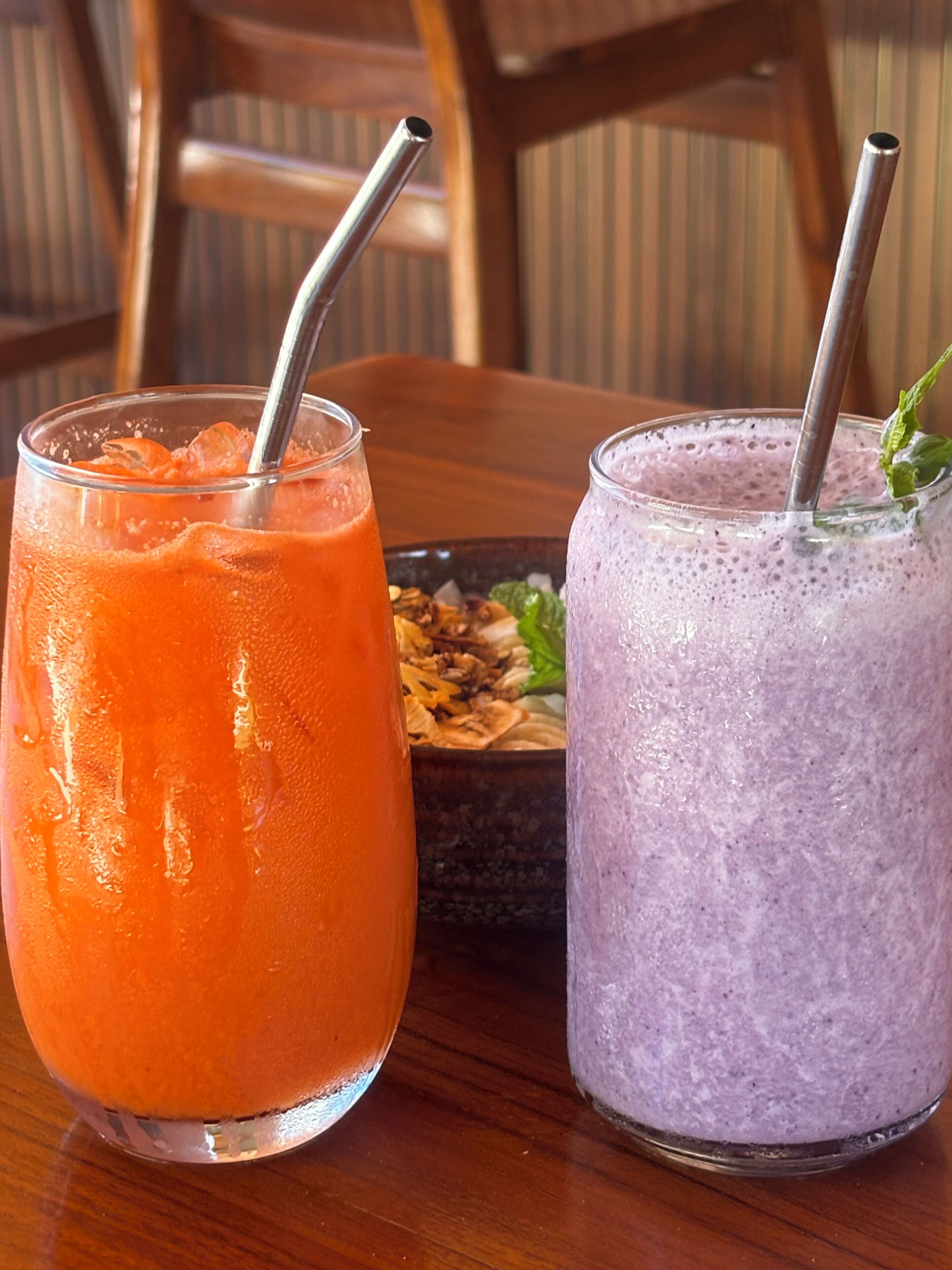 Two glasses of smoothie on a wooden table with a blurred background.