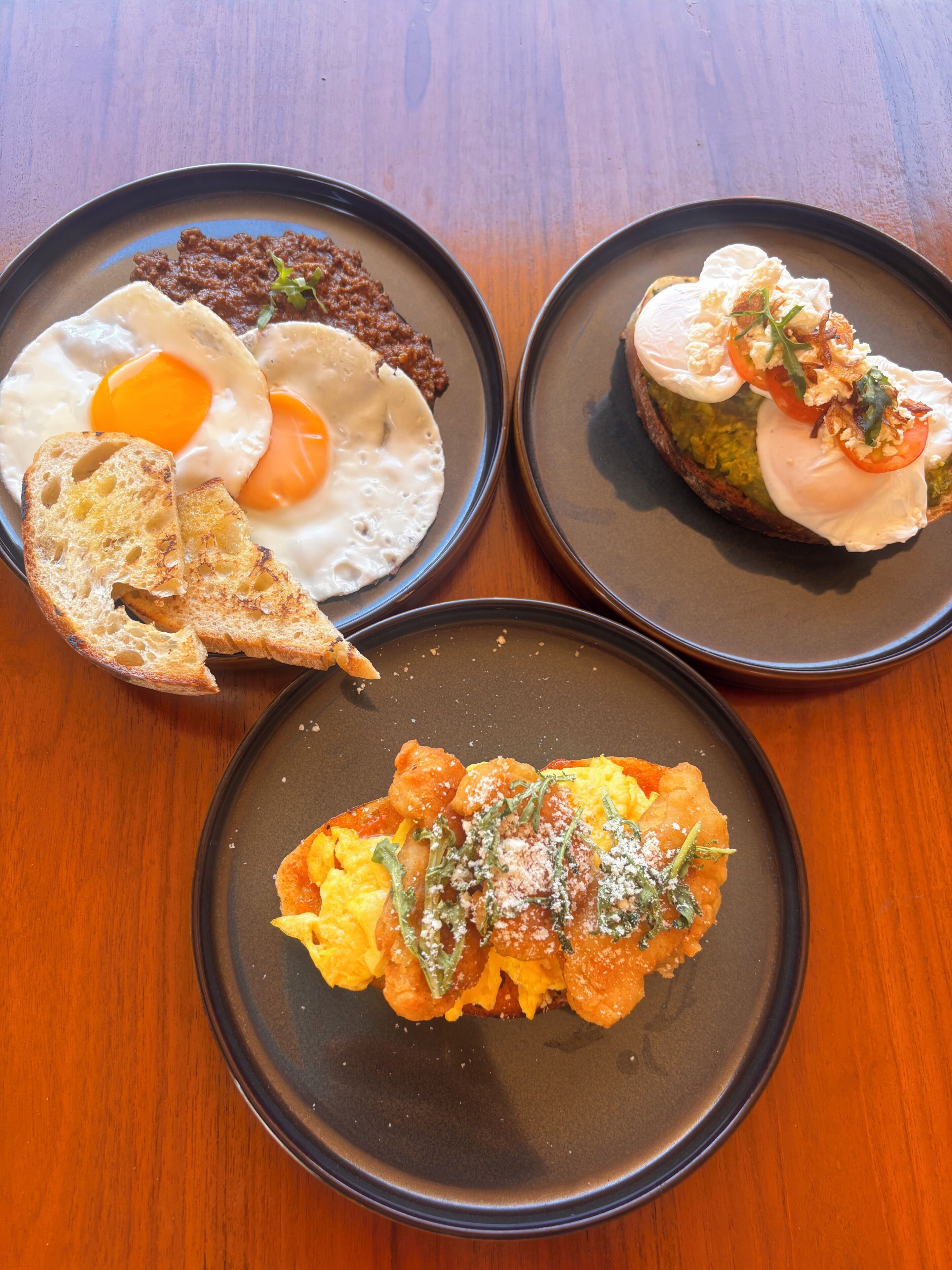 Three plates of food on a wooden table.