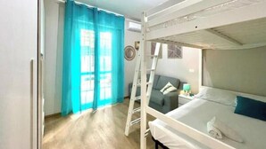 Une chambre avec un lit superposé, une échelle, un canapé et une petite table.
