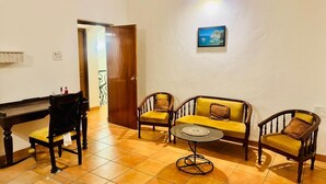 A room with a wooden desk, two armchairs, a sofa, and a small round table. - Independent Bungalow for rent at Siolim. Next to main market with parking for 2 (Siolim)