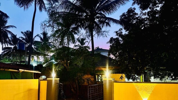 A gated entrance with a metal gate, a concrete wall, and a pathway leading to a building. - Independent Bungalow for rent at Siolim. Next to main market with parking for 2 (Siolim)