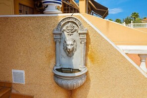 A building with a textured facade, a decorative lion head relief, and a tiled roof. - Holiday Home Torrevieja (Torrevieja)