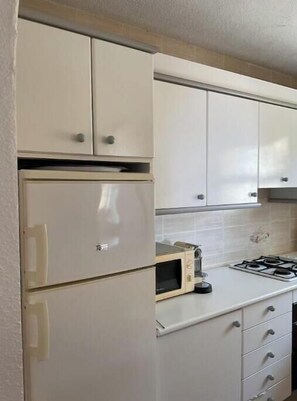 A kitchen with white cabinets, a built-in microwave, and a gas stove. - Apartment with sea views in Cumbre del Sol (Cumbre del Sol)