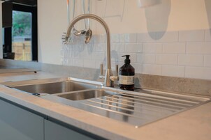 A modern kitchen with a stainless steel sink, a faucet, and a soap dispenser.